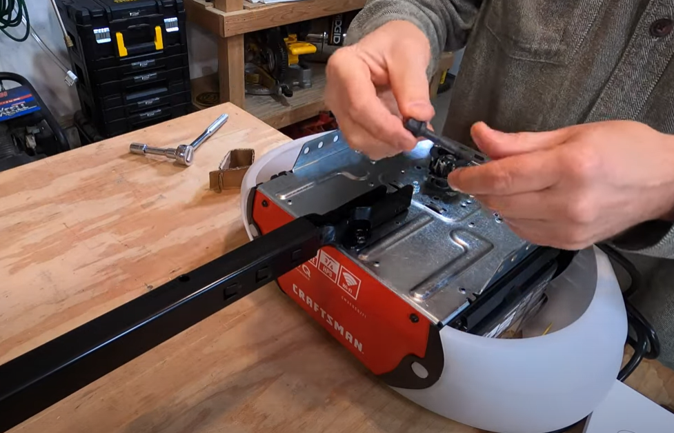 a technician in Punta Gorda, FL, repairing a garage door opener by adjusting the settings on a small control panel. The garage door is partially open, revealing the modern home exterior in the background.